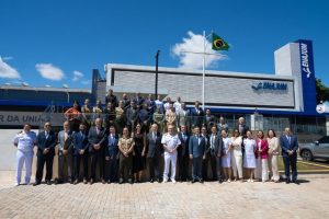 Foto mostra um grupo de 41 pessoas, entre civis e militares, que posam em uma área externa em frente à sede da Enajum, em Brasília. Eles estão agrupados em três fileiras, e ao fundo está um mastro com a bandeira do Brasil