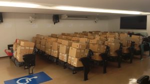 Imagem mostra o auditório do TJMMG com caixas de processos acondicionadas sobre cadeiras