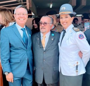 A foto mostra três pessoas. À esquerda está o desembargador coronel Osmar Duarte Marcelino, de terno e gravata azul, e camisa branca. Ao centro, o desembargador Jadir Silva, de terno cinza, camisa branca e gravata amarela. À direita, pela coronel Jordana de Oliveira Filgueiras Daldegan, de farda branca do CBMMG