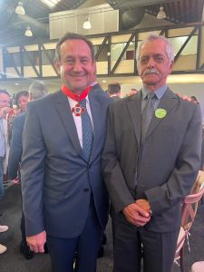 A imagem mostra à direita o desembargador Sócrates Edgard dos Anjos vestindo terno, camisa e gravata cinzas, ao lado do presidente do TJMG, desembargador Luiz Carlos de Azevedo Corrêa Junior, que veste terno e gravata azul, camisa branca, e usa a Grande Medalha concedida pelo Governo de Minas. Eles estão no Centro de Artes e Convenções da Ufop
