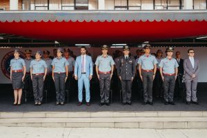 A imagem mostra vários formandos fardados do CBMMG posicionados lado a lado, entre homens e mulheres uniformizados. Na fileira da frente, o primeiro homem da direita para a esquerda, está o juiz Bruno Cortez Torres Castelo Branco vestindo um terno cinza claro e usando uma gravata azul claro