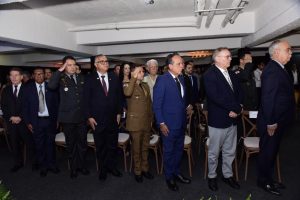 A imagem mostra um grupo de autoridades e convidados em pé durante a cerimônia de inauguração da sede do Centro de Atendimento Jurídico da AOPMBM. Na primeira fileira há oito homens alinhados. Da direita para a esquerda, o primeiro, é o desembargador Rúbio Paulino Coelho; o terceiro é o desembargador James Ferreira Santos; e o último é o desembargador Fernando Antônio Nogueira Galvão da Rocha