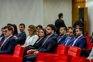 A imagem mostra um grupo de magistrados, entre homens e mulheres, no auditório do Salão Nobre do Superior Tribunal de Justiça. Os homens vestem terno, e há duas mulheres na imagem, uma vestida de branco e outra de preto. Eles estão sentados em poltronas vermelhas. O juiz Antônio Moreno Boregas e Rego é o segundo da esquerda para a direita. Ele está de braços cruzados, olha para a câmera, e está vestindo terno e camisa azul