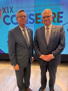 A imagem mostra dois homens em pé, um ao lado do outro. À esquerda está o desembargador Osmar Duarte Marcelino, vestindo terno cinza e gravata clara. Ao seu lado está o ministro Edson Fakin, vestindo terno cinza escuro e gravata clara. Ao fundo, aparece um painel escrito 19º Encontro do Conselho de Presidentes dos Tribunais de Justiça do Brasil. Conzépre.