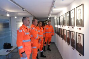 A imagem mostra os alunos da Academia de Bombeiros Militar durante sessão de julgamento do Tribunal Pleno. Todos vestem uniformes do bombeiro militar na cor laranja. Eles estão sentados em cadeiras vermelhas do Plenário do TJMMG. As paredes ao fundo são brancas.